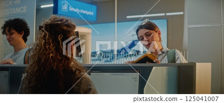 Multiethnic Passengers at Airport Check-in Counter: Female Airline Worker Checking Documents 125041007