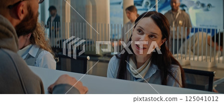 Airport Check-in Counter: Female Airline Agent Checking Boarding Documents of Passenger Airport Check-in Counter: Female Airline Agent Checking Boarding Documents of Passenger 125041012