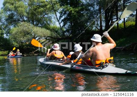 Family with children on rafting trip in Group kayak trip of different ages, adults, elderly. Rowing boat on the river, a water hike, summer adventure. 125041116