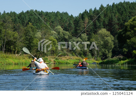 Family with children on rafting trip in Group kayak trip of different ages, adults, elderly. Rowing boat on the river, a water hike, summer adventure. Family with children on rafting trip in Group kayak trip of different ages, adults, elderly. Rowing boat on the river, a water hike, summer adventure. 125041124