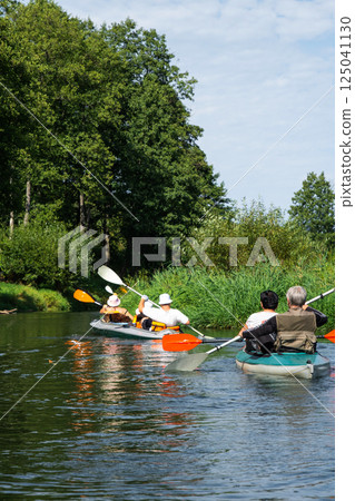 Group kayak trip for seigneur and senora. An elderly couple And adult rowing boat on the river, a water hike, a summer adventure. Age-related sports, mental youth and health, tourism, active old age Group kayak trip for seigneur and senora. An elderly couple And adult rowing boat on the river, a water hike, a summer adventure. Age-related sports, mental youth and health, tourism, active old age 125041130