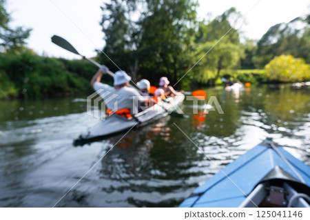 Family with children on rafting trip in Group kayak trip of different ages, adults, elderly. Rowing boat on the river, a water hike, summer adventure. 125041146