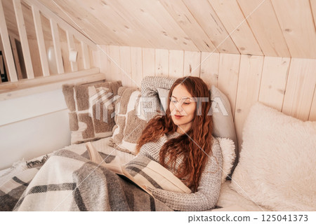 Woman Reading Book at Cozy Log Cabin in Winter Woman Reading Book at Cozy Log Cabin in Winter 125041373