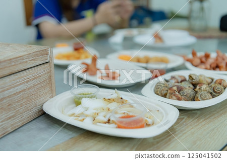 A variety of seafood dishes served on plates, featuring fresh ingredients and vibrant colors, ideal for culinary enthusiasts. 125041502