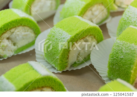 Delicious green cream rolls with a fluffy texture and sweet filling, perfect for dessert lovers. 125041587