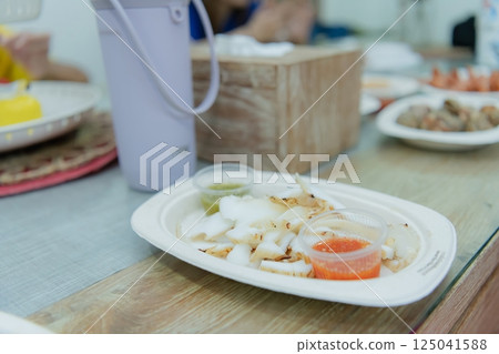 Delicious seafood dish served with sauces on a wooden table, showcasing a vibrant culinary experience. 125041588