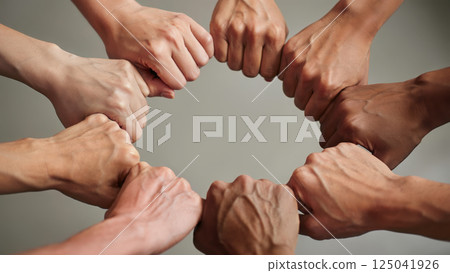 Group of diverse people joining fists of different skin tones, symbolizing multicultural society unity, collective effort and inclusion. Teamwork connection and solidarity, inclusivity concept 125041926