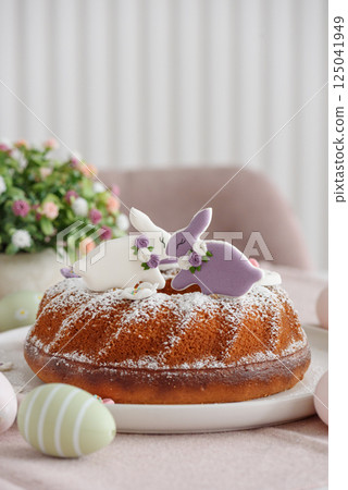 Traditional easter cakes with icing decorated with gingerbread cookies in shape of rabbits on white wooden table 125041949