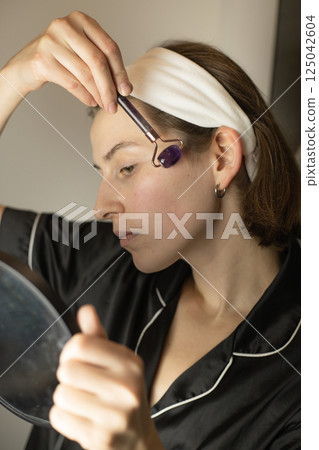 woman doing facial massage with roller massager 125042604