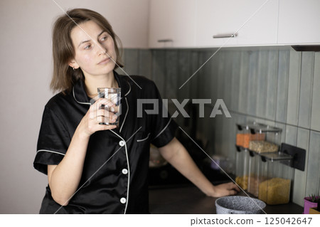 woman drinking water from a glass in the kitchen woman drinking water from a glass in the kitchen 125042647