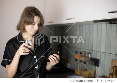 A woman taking vitamins in her kitchen 125042648