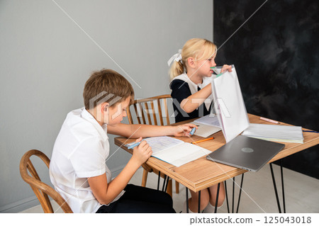 Children School Homework Table Studying - Boy and girl in school uniform sitting at a table, doing homework. 125043018