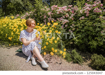 A woman is sitting on the ground in a field of yellow flowers 125043047