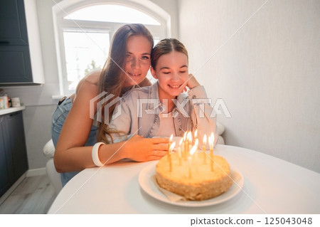 Birthday Cake Candles Mother Daughter: Celebrating a birthday at home with family, lighting candles on a cake, joyful moment. Birthday Cake Candles Mother Daughter: Celebrating a birthday at home with family, lighting candles on a cake, joyful moment. 125043048