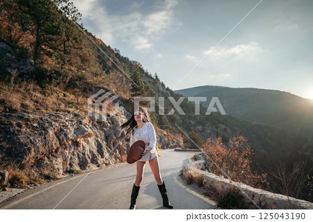 Woman road mountain. A woman in a white sweater, black boots and a hat walks along a winding alpine path between the mountains at sunset in late summer. The concept of travel. Woman road mountain. A woman in a white sweater, black boots and a hat walks along a winding alpine path between the mountains at sunset in late summer. The concept of travel. 125043190