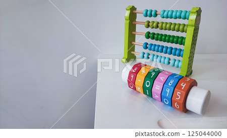 Children's wooden construction set, abacus, on a white table. Concept of children's development, montesori Children's wooden construction set, abacus, on a white table. Concept of children's development, montesori 125044000