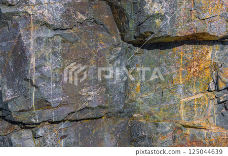 Weathered metamorphic rock texture, colorful stone surface, natural pattern, outdoor, daylight 125044639