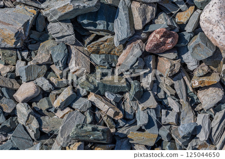 Pile of various rough stones and rock fragments under bright sunlight. 125044650
