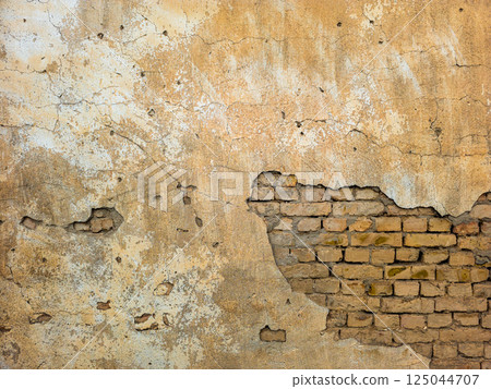 Old brick wall with peeling plaster and exposed bricks 125044707