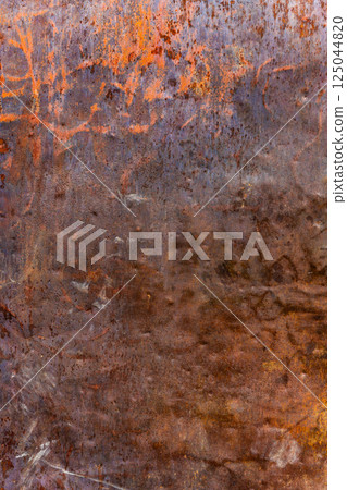 Heavily rusted metal surface with remnants of orange paint, showing deep corrosion and texture. Heavily rusted metal surface with remnants of orange paint, showing deep corrosion and texture. 125044820