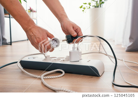 Man using power strip, multiple electrical devices 125045105