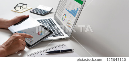 Man using tablet and laptop, financial app Man using tablet and laptop, financial app 125045110