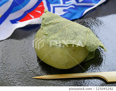 慶祝男孩節的年糕！以鯉魚旗為背景的柏餅（一種草餅）的照片 125045292