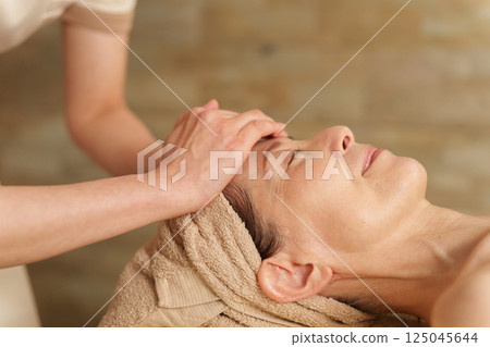 Senior woman receiving a head massage at a beauty salon Senior woman receiving a head massage at a beauty salon 125045644