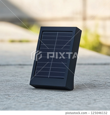 Small solar panel positioned on a concrete surface under natural light providing an eco-friendly energy solution for outdoor applications 125046132