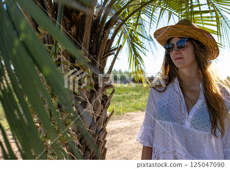 Young woman with rattan hat and sunglasses enjoying nature and summer. Young woman with rattan hat and sunglasses enjoying nature and summer. 125047090
