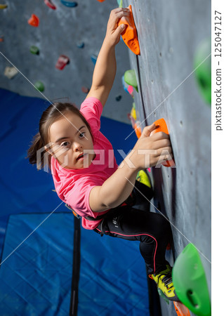 Child Climbing on Indoor Rock Wall in Bright Pink Shirt During Afternoon Practice Session 125047127