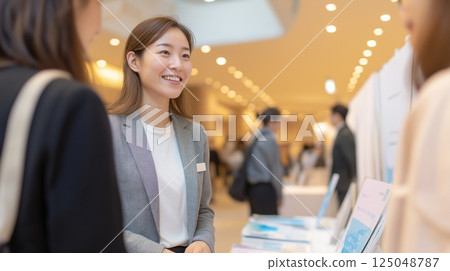 一名女員工在展覽會上與參觀者交談的商業場景 一名女員工在展覽會上與參觀者交談的商業場景 125048787