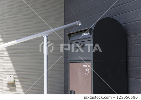 Delivery box and handrail placed in front of the entrance of a detached house Delivery box and handrail placed in front of the entrance of a detached house 125050580