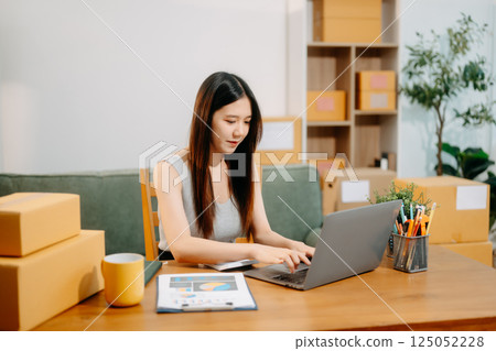 Young business owner woman prepare parcel box and standing check online orders for deliver 125052228