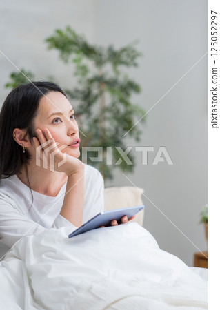 Woman using tablet in bed | Reading and studying | Healthy living image | Well-being girl | Well-being 125052297