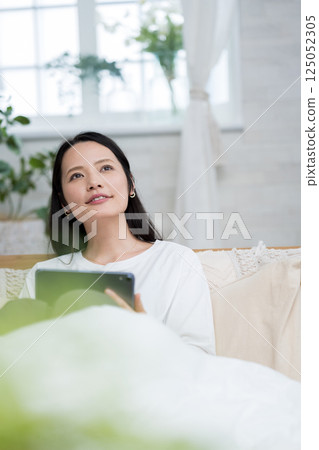 Woman operating a tablet indoors | Reading and studying | Healthy living image | Well-being girl | Well-being 125052305