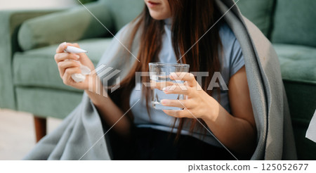 Young Asian woman suffering from flu symptoms, covered with a blanket on a sofa. Concept of illness, healthcare, Young Asian woman suffering from flu symptoms, covered with a blanket on a sofa. Concept of illness, healthcare, 125052677