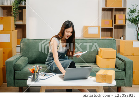 Young business owner woman prepare parcel box and standing check online orders for deliver 125052925