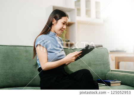Asian woman using the smartphone and tablet on the sofa at home Asian woman using the smartphone and tablet on the sofa at home 125052953
