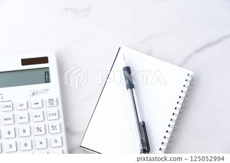Image of working at a desk with a calculator, pen, and notepad Image of working at a desk with a calculator, pen, and notepad 125052994