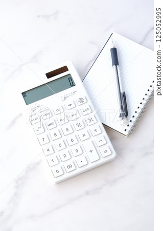 Image of working at a desk with a calculator, pen, and notepad Image of working at a desk with a calculator, pen, and notepad 125052995