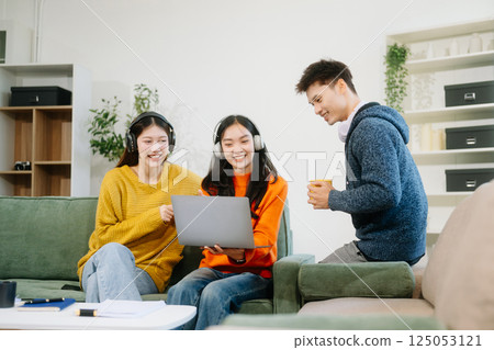 vibrant teamwork, creativity, and learning with young adults using laptops and headphones  in cozy 125053121