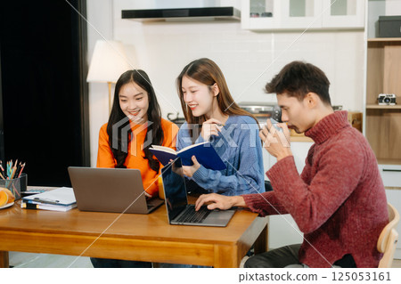 Teamwork and creativity with young adults collaborating on laptops and tablets in a cozy workspace. Teamwork and creativity with young adults collaborating on laptops and tablets in a cozy workspace. 125053161