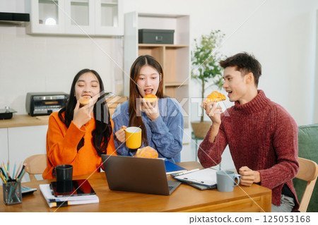 Teamwork and creativity with young adults collaborating on laptops and tablets in a cozy workspace. Teamwork and creativity with young adults collaborating on laptops and tablets in a cozy workspace. 125053168