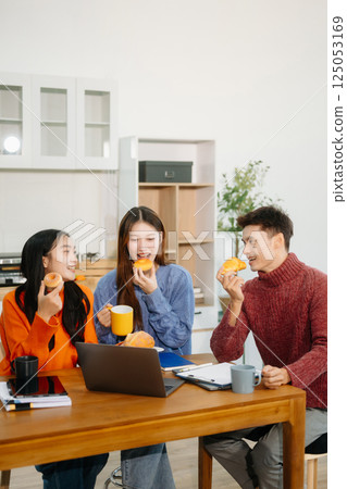 Teamwork and creativity with young adults collaborating on laptops and tablets in a cozy workspace. Teamwork and creativity with young adults collaborating on laptops and tablets in a cozy workspace. 125053169