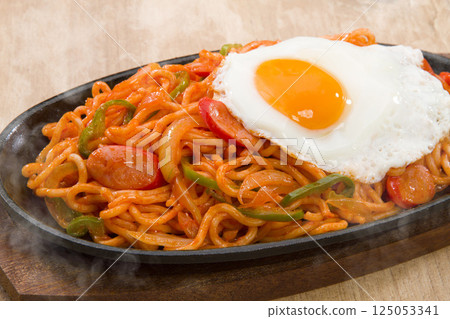 Neapolitan pasta on a hot plate topped with a fried egg 125053341