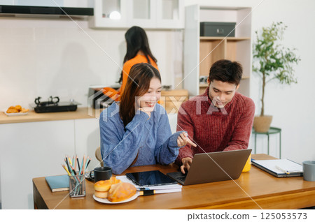 Teamwork and creativity with young adults collaborating on laptops and tablets in a cozy workspace. Teamwork and creativity with young adults collaborating on laptops and tablets in a cozy workspace. 125053573