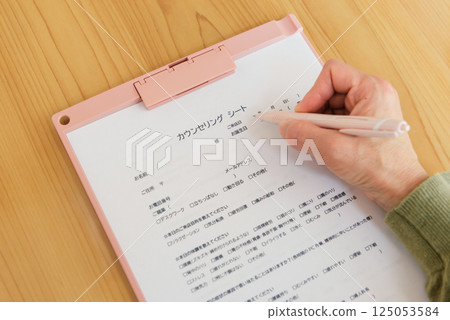 Woman's hands writing on a counseling sheet 125053584