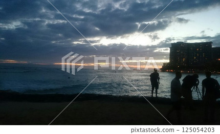 Hawaii: Surfers looking out at the ocean from a cloudy beach 125054203