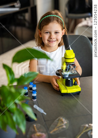 Portrait of little girl with green microscope. Concept of curiosity and early scientific exploration 125054238